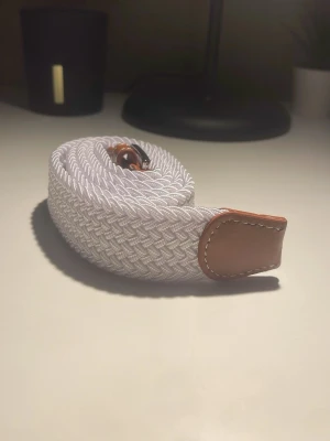 Vitt flätat bälte  - Snyggt vitt flätat bälte med bruna läderdetaljer vid ändarna. Säljer för ett bra pris och kan diskuteras 