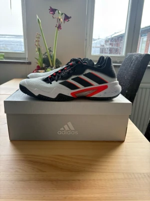 Adidas sportskor svart/vit/röd - Hej!  NYPRIS 1599kr Jag säljer min padel/tennis skor som jag köpte igår och modellen passade ej mig spelat med dom i 15-20 minuter och får ej lämna tillbaka dom därav säljer jag dom lite billigare än original pris