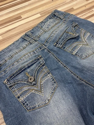 Blåa Angels jeans med broderade fickor - Säljer ett par blåa jeans från Angels med snygga broderade bakfickor och kontrastsömmar. Jeansen har en loose passform och utsvängda ben, perfekt för en avslappnad stil. Tänk på att dom inte passar mig helt i midjan🥲🙏, midjemåttet: 40cm tvärsöver, innerbenslängden: 78cm. Pris går alltid att diskuteras, skriv för för fler bilder!💝🫰