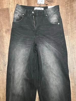 Svarta super baggy jeans - Säljer ett par svarta super baggy jeans med tvättade detaljer och bred passform. Jeansen har hög midja, klassiska fem fickor och dragkedja fram. Perfekta för en avslappnad och trendig look.