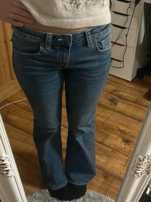 Blå bootcut jeans med låg midja - Säljer ett par klassiska blå bootcut jeans med låg midja. Jeansen har fem fickor, bälteshällor och stängs med knapp och dragkedja. Perfekta för dig som gillar en avslappnad men ändå snygg look. De är ifrån H&M och är i storlek 36! Perfekt skick och inga defekter. Använda fåtalgånger. Pris är diskuterbart 