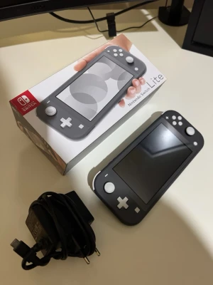 Nintendo Switch Lite svart  konsol - Nintendo Switch Lite i snygg svart färg med vit knappdesign. Handhållen spelkonsol med slimmad form och matt finish. Perfekt för gaming on-the-go. Laddare och originalkartong medföljer.