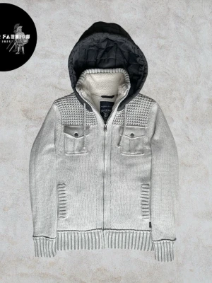 Stickad fodrad cardigan jacka - Stickad cardigan jacka i ljusgrå med mjukt vitt fleecefoder och quiltad mörkblå stoppning på insidan för extra värme. Fast huva, bröstficka med knapp och sidoficka. Ribbstickade muddar, nederkant och axelpartier. Skicket är nästintill ny utan några defekter och knappt använd. Storlek L men kan även passa M. Hör av dig för mått!                                                                            ~ Nypris okänt liknande säljs för 800-1200kr  | Vårt pris 999 kr. Alla följare får rabatt, följ