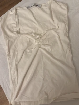 Krämvitt topp med rosett - Sött krämvitt topp från lager157 med rynkade detaljer framtill och liten rosett vid bysten. Dekorerat med spets längs urringningen för en romantisk känsla. Mjukt och lätt material. Priset kan diskuteras 💕💕