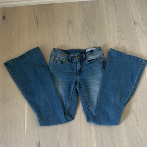 Blå bootcut jeans från Vero Moda - Snygga blå bootcut jeans från Vero Moda med klassisk femficksdesign och ljus tvätt. Jeansen har normal midja och är tillverkade i mjukt denimtyg med lätt stretch. Perfekta för dig som gillar en retroinspirerad look med utsvängda ben. Kan sänka priset vid snabba affärer