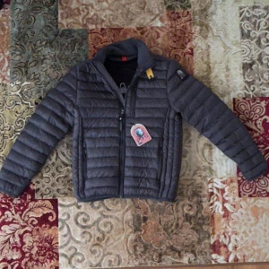 Mörkgrå dunjacka från Parajumper - Snygg mörkgrå dunjacka från Parajumpers med klassisk broderad logga på ärmen och gul detalj vid kragen. Jackan har quiltad design, dragkedja framtill och långärmade ärmar. Perfekt för kyliga dagar och har en clean, sportig look.