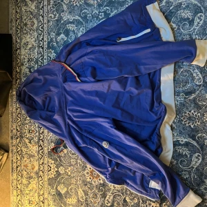 Blå hoodie från Moncler  - Blå hoodie från Moncler med vit insida och vita muddar. Perfekt för dig som gillar streetwear och snygga detaljer. Skick 10/10 fin som ny