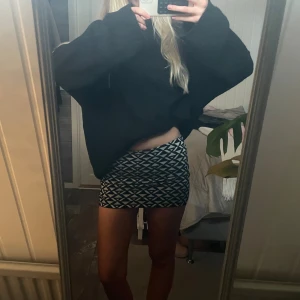 Minikjol - Säljer en svartvit lågmidjad, kortkjol med grafiskt mönster i trianglar. Kjolen är tight och har en enkel, rak passform som sitter snyggt på höften. Perfekt för dig som gillar en trendig och stilren look. Materialet känns mjukt och stretchigt.