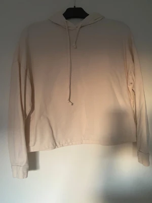 Beige hoodie från ONLY i storlek L - Säljer en beige hoodie från ONLY i storlek L. Tröjan har huva med snörning, midjekort och är långärmad. Materialet är mjukt och känns skönt mot huden. Enkel och stilren design utan mönster eller tryck.
