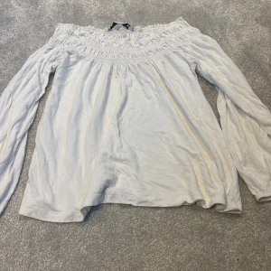 Vit offshoulder blus från 157, XS - Säljer en vit blus från 157 i storlek XS med offshoulder-design och smockad överdel. Blusen har långa, luftiga ärmar med resår vid ärmslut och är gjord i mjuk bomull. Perfekt för dig som gillar en chill och feminin stil.