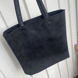 Svart mocka shoppingväska I Want It All - Stilren svart shoppingväska i mocka med två rejäla handtag och enkel design. Väskan har tryckknappsstängning och ett innerfack med dragkedja. Perfekt för dig som gillar minimalistisk look och vill ha plats för allt du behöver. 💕💕💕Rymlig å fin! Skriv vid frågor. Pris kan diskuteras 💕 Bag  #Väska  #Vinted #Fynd #Secondhand #fashion #VintedUK #selling #Kappa #Coat #Kappa #Jacka #Vinted  #Fynd  #😍 #Loppis  #Sweden #Esprit  #Märke  #mycket fint skick! #Blue