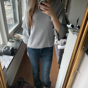 Grå stickad tröja med volangärmar🩷 - Supersnygg grå stickad tröja med bred rund hals och unika volangärmar som ger en extra cool vibe. Modellen är lite loose och passar perfekt till jeans. Materialet är mjukt och skönt, och färgen är neutral vilket gör den enkel att matcha. Passar till allt!!💕använd få gånger och den är från BIKBOK❣️