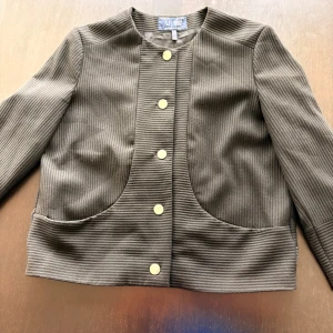 Svart ribbad cardigan jacka Armani Jeans - Snygg svart cardigan jacka från Armani Jeans med ribbad struktur och guldfärgade knappar med logga. Jackan har rund hals, stora fickor framtill och långärmad design. Perfekt för dig som gillar stilrena detaljer och exklusiv känsla.