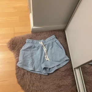 Ljusblå shorts från Etirel med snörning - Säljer ett par ljusblå mjuka shorts från Etirel med vit snörning i midjan och två sidofickor. Perfekta för chill dagar eller träning. De har en loose passform och är gjorda i bomull för extra komfort.hör av dig om du har några frågor eller funderingar 💕