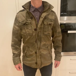 Field jacket från Abercrombie & fitch - En otroligt snygg Field jacka från Abercrombie & fitch med camoflauge mönster. Jackan har många feta detaljer och har ett mycket bra skick, med en vintage look. Jackan är i storlek M och är ett riktigt kap! Har du några frågor kring mått osv? Fråga på!