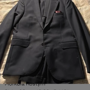 Mörkblå kostym These Glory Days - Snygg mörkblå kostym från These Glory Days med klassisk kavaj och matchande byxor. Kavajen har två fickor med lock, bröstficka och smal passform. Byxorna är raka med pressveck. Perfekt för dig som vill ha en stilren och tidlös look.