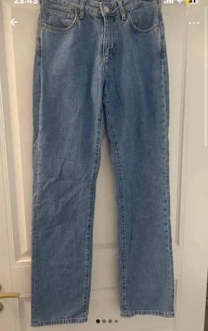 Blå straight jeans från Never Denim - Snygga blå jeans från Never Denim med raka ben. Klassisk femficksmodell med silverfärgad knapp. Perfekt passform för dig som gillar en avslappnad och tidlös look.