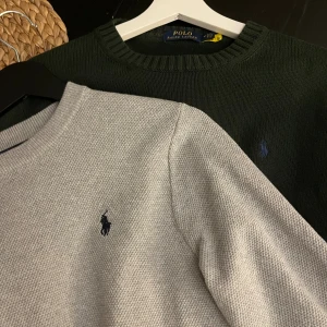 Stickade tröjor från Polo Ralph Lauren - Två stickade tröjor från Polo Ralph Lauren, en i mörkgrön och en i ljusgrå. Båda har rund hals och den klassiska broderade loggan på bröstet. Perfekt för dig som gillar stilrena och tidlösa plagg med skön passform.