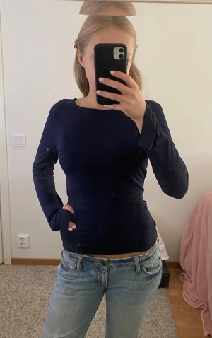 Mörkblå långärmad tröja - Säljer en mörkblå långärmad topp som är lite urringad, halvt öppen vid handen men med lång ärmlängd 💞 skriv vid intresse!