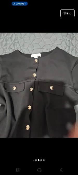 Svart kofta med guldknappar H&M - Stilren svart kofta från H&M med snygga guldknappar framtill och två fejkade bröstfickor. Croppad modell med lång ärm och rund halsringning. Perfekt för dig som gillar en klassisk men trendig look. I väldigt fin skick bara provat utan prislapp storlek S.