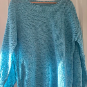 Turkos stickad tröja med lång ärm - Mysig turkos stickad tröja med lång ärm och rund hals. Perfekt för dig som gillar en chill och enkel stil. Tröjan har en loose passform och är gjord i ett mjukt stickat material som känns skönt mot huden.