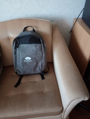 Grå ryggsäck Motala kommun - Snygg grå ryggsäck med svart ovandel och dragkedja. Framsidan har Motala kommuns logga tryckt i vitt. Perfekt storlek för skola eller häng med kompisar, med justerbara axelremmar och praktiskt ytterfack.