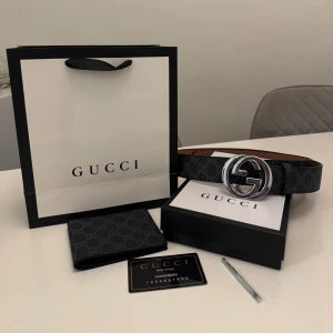 Svart Gucci GG Supreme bälte med silver-spänne - Säljer ett svart Gucci GG Supreme bälte med ikoniskt silverfärgat GG-spänne. Bältet har ett diskret mönster med Guccis logga över hela bandet och är tillverkat i exklusivt skinn. Perfekt accessoar för att lyfta din outfit med lyxig känsla och stil.