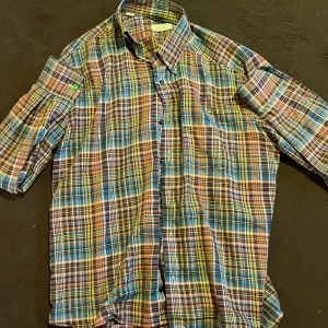 Rutig skjorta från Eton flannel - Snygg rutig skjorta från Eton i flannel med färger som blå, gul, orange och vit. Klassisk krage, knappar framtill och korta ärmar. Perfekt för dig som gillar färgstarka och mönstrade plagg med lite edge.Nypris är 2000kr mitt pris 600kr