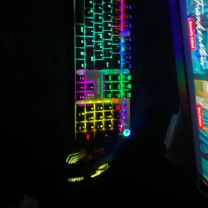 Cepter RGB Gaming-tangentbord och mus - Snyggt RGB-belyst gaming-tangentbord och mus från Cepter. Tangentbordet har mekaniska knappar och flera färginställningar, medan musen har justerbar DPI och matchande RGB-belysning. Båda enheterna ser ut att vara i gott skick utan synligt slitage eller defekter.