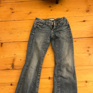 Blå bootcut jeans från Gina Tricot - Snygga blå jeans från Gina Tricot i storlek 158. Modellen har klassisk femficksdesign, ljus tvätt och bootcut-ben som ger en cool siluett. Jeansen är tillverkade i jeansmaterial med tydliga sömmar och knappstängning framtill.