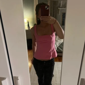 rosa topp med rosett  - Supersöt rosa linnetopp från Zara med fyrkantig urringning och breda axelband. Toppen har en stor rosett i ryggen och en snygg öppen rygg. använd cirka 3 gånger 