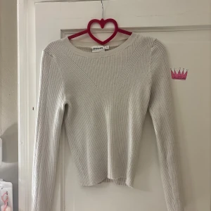 Ribbad beige stickad tröja Kappahl - Snygg ribbad stickad tröja från Kappahl i beige färg. Modellen har rund hals och långärmade ärmar, med coola ribbade detaljer som ger en fräsch look. Perfekt att styla med jeans eller kjol för en chill vibe.