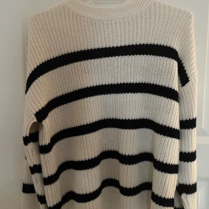 Randig stickad tröja från lager 157 - Säljer en oversized stickad tröja från lager 157 i vitt med svarta breda ränder. Tröjan har rund halsringning och långa ärmar. Perfekt för dig som gillar en chill och trendig look.