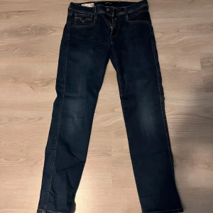 Replay mörkblå jeans  - Snygga mörkblå jeans från Replay med klassisk femficksdesign och kontrastsömmar. Modellen har rak passform och normal midja, med Replay-logga på bakfickan. Jeansen är tillverkade i slitstarkt denim och har dragkedja framtill.