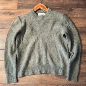 Ulltröja från These glory Days | Strl S - Tröja i 100% lammull i mycket bra skick. Färgen är en kombination av grå och oliv, kanske lite khaki.