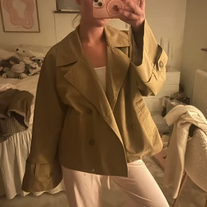 Beige croppad trenchcoat med knappar - Säljer en beige croppad trenchcoat med breda slag och dubbelknäppning. Knappt använd i storlek 36💓💓