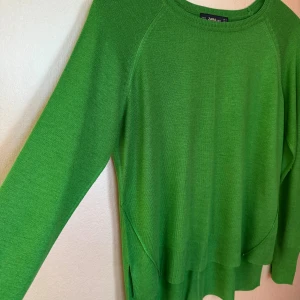 Grön tunnstickad tröja från Zara - Snygg, tunn grön stickad tröja från Zara med rund hals, långa ärmar. Tröjan har ribbade muddar och en cool slitsdetalj på sidorna vid nederkanten. Lite kortare framtill, jättefint fall. Snygg detalj med söm mitt bak.