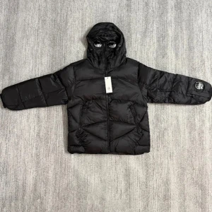 CP Company pufferjacka med huva - Säljer feta pufferjacka från CP Company med ikonisk lins på ärmen och huva. Finns i svart, blå och olivgrön. Jackan har dragkedja framtill, två snedställda fickor med zip och quiltad design. Perfekt för dig som vill ha en cool och varm jacka med street-vibe. Skriv för mer info! 