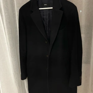 Svart rock från BOSS linjen -  Hugo Boss (BOSS-linjen, inte HUGO).  Modellnamn  BOSS Stratus3 (Identifierat via artikelnummer och konstruktion).  Artikel-/stilkod  10192381 Underkod/version: 01 Färgkod: 402 (mörk marin, ser nästan svart).  Storlek  EU: 48 Den är i kanon skick, har varit mestadel i  garderoben på sistonde. Köpt på NK i stockholm för flera år sedan. Jag är 177cm och 78kg, passar mig perfekt, skulle säga den passar 172-185  cm under 85kg i vikt