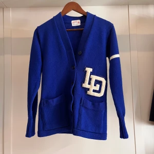 Blå kofta från Coane med patch - Retro blå kofta från Coane i ett riktigt bra skick. Koftan är i storlek XS och sitter ganska slim. Perfekt för hösten och vintern. Hör av er om intresse!