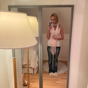 Ljusrosa tun glittrig halsduk med fransar  - Supersöt ljusrosa halsduk med glittriga detaljer och långa fransar i ändarna. Tunn och lätt, perfekt att slänga över en enkel outfit för att få lite extra stil. Passar dig som gillar en feminin och trendig look.