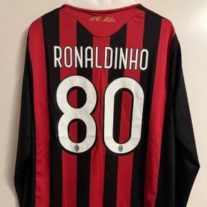 AC Milan Ronaldinho 2009/2010 fotbollströja - Lag och säsong: AC Milan Hemmatröja 2009/2010 Namn: Ronaldinho #80 Storlek: L Skick: Oanvänd med lapp kvar. Reprint