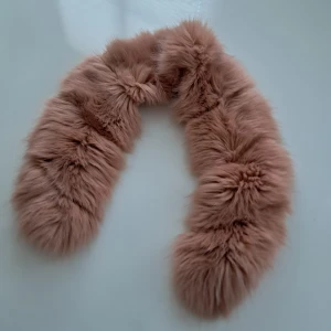 Ljusrosa fluffig fuskpäls krage  - Supermjuk och lång ljusrosa halsduk i fluffig fuskpäls med glansig satinbaksida. Perfekt för att ge din outfit en lyxig och cozy vibe. Snygg att slänga över jackan eller kappan när det är kallt ute.