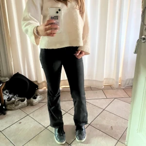 Svarta bootcut jeans från Filippa K - Modell Lily shiny jeans, går ej att få tag på längre.  Snygga svarta jeans från Filippa K med bootcut-modell och hög midja. Jeansen har klassisk femficksdesign, dragkedja och knapp framtill. Materialet är stretchigt jeans för en bekväm passform och de har en stilren look som passar till allt.