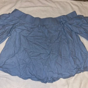 Offshoulder - Snygg blå offshoulder topp med bred resår upptill och vida, korta ärmar. Perfekt för dig som gillar en avslappnad men trendig stil. Legat i en kasse därför skrynklig. Passar även storlek s