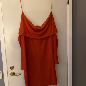 Ribbad orange kortklänning med tunna band - Säljer en ribbad orange kortklänning och  snygg . Klänningen har en loose passform och är tillverkad i ett mjukt, stretchigt material som känns bekvämt mot huden. Perfekt för dig som gillar färg och vill sticka ut.Frakt ingår inte 