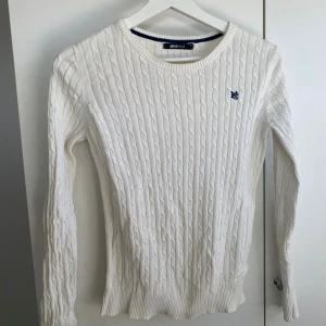 Vit kabelstickad tröja Gina Tricot - Vit kabelstickad tröja från Gina Tricot med rund halsringning och diskret blå brodyr på bröstet. 