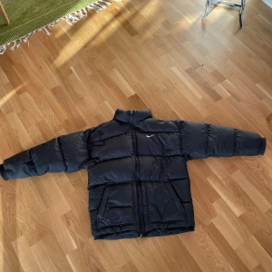 Svart pufferjacka från Nike XL - Vintage svart Nike puffer/dunjacka. Jackan är i storlek XL men jag skulle säga att den snarare passar XS-M ❗️FINNS NÅGRA SMÅ SKADOR❗️så skriv till mig så skickar jag bilder på de och ger mer info! :) Inga större skador på jackan utöver det. Pris kan diskuteras, skriv vid intresse eller om du har några frågor!:)