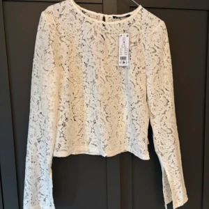 Blus  - Superfin vit blus med utsvänga armar och slits. Dragkedja på sidan och knap där bak. Aldrig använd!!! passar även en S