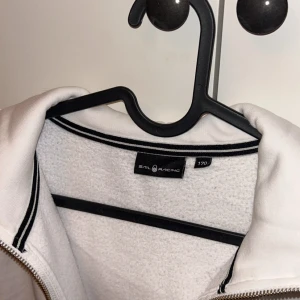 Vit hoodie från Sail Racing med dragkedja - Vit hoodie från Sail Racing med hel dragkedja storlek 170/XS/S. Den är använd fåtal gånger och är i jättebra skick! Säljer då den som sagt inte kommer till användning🌸
